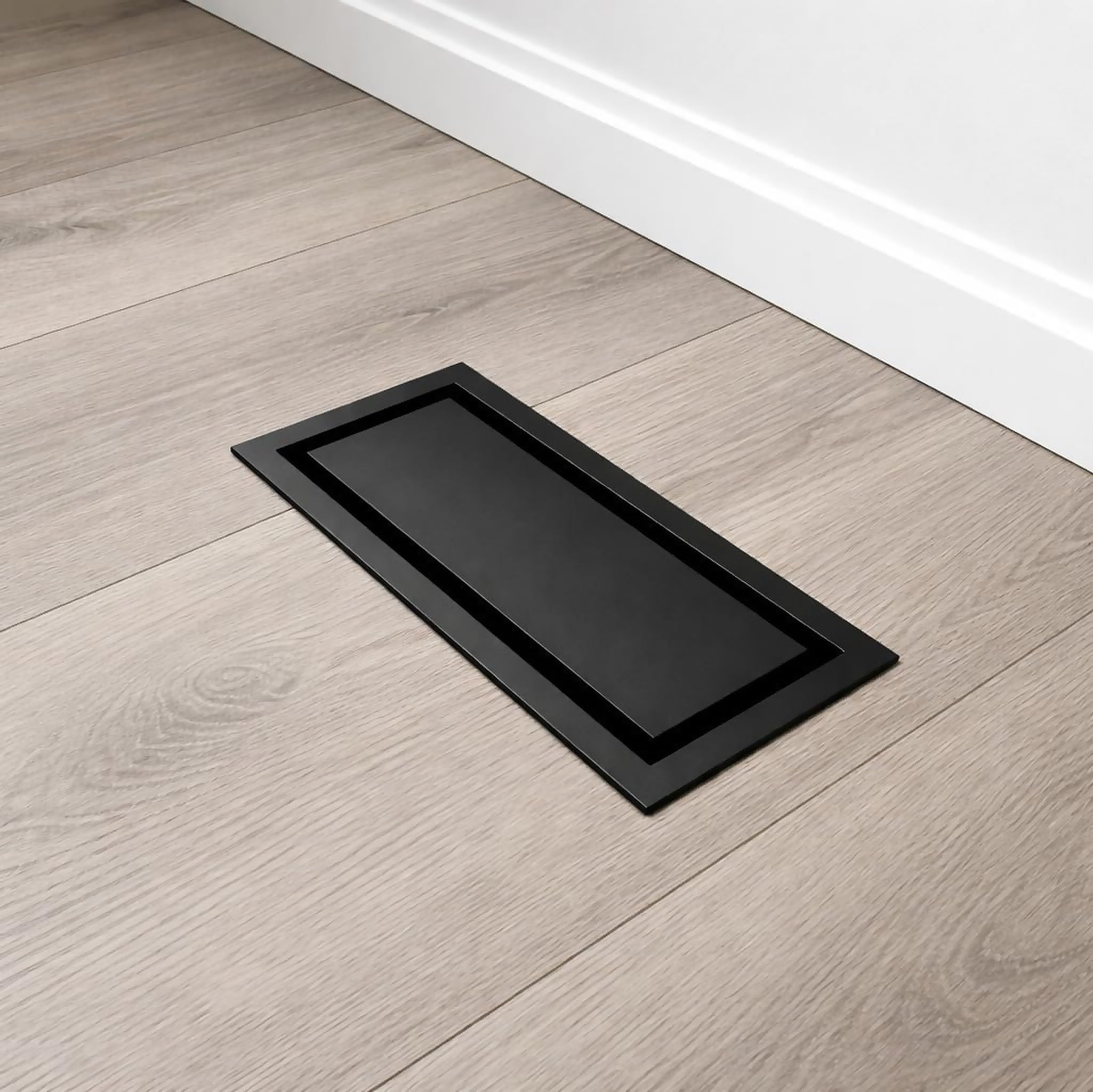Black undermount flush metal floor vent installed level with light wood flooring — Khan Supply CO